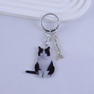 Detailed view of black and white tuxedo cat resin keychain with silver fishbone charm
