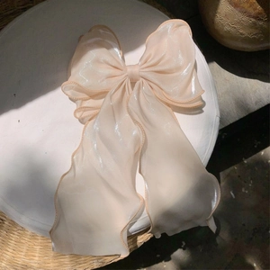 Close-up of champagne iridescent organza bow hair clip with elegant ruffled edges