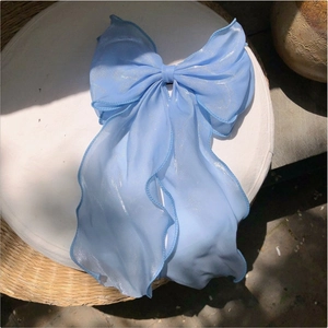 Detail of light blue bow hair clip with shimmering fabric and long ribbons for women