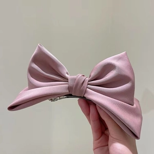 Dettaglio del fermaglio per capelli a fiocco in raso rosa cipria con chiusura a molla