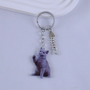 Detail view of acrylic grey British Shorthair cat keychain with silver fishbone charm