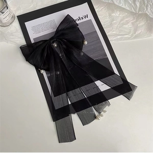 Dettaglio di un elegante fiocco per capelli in tulle nero decorato con perle delicate