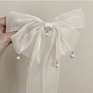 Dettaglio del fiocco in organza bianca con ciondoli di perle e texture scintillante