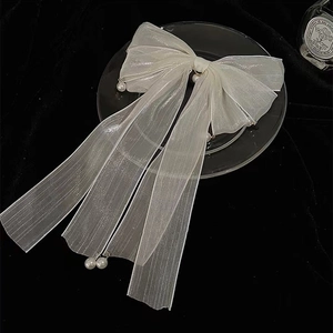 Dettaglio del fermaglio per capelli con fiocco in organza bianca, nastri e perle