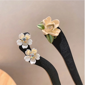 Macro detail of creamy 3D flower hair pin with green leaves and rhinestone accents
