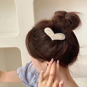 Pince à cheveux en acétate en forme de cœur nacré sur une coiffure élégante de femme