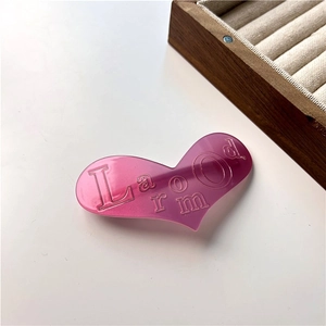 Détail macro d'une pince à cheveux en cœur rose avec des lettres pailletées en relief