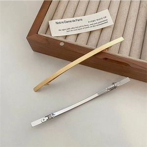 Elegantes Set aus gold- und silberfarbenen Haarspangen aus Metall auf Holztablett