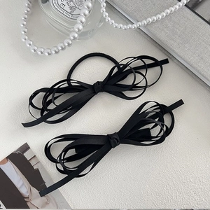 French vintage black silk ribbon bow hair clip set on a minimalist elegant background