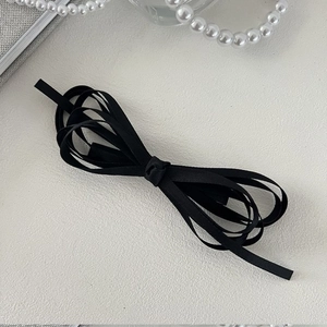 Elegant black satin ribbon bow hair clip with long streamers on minimalist background