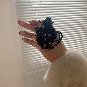 Close-up of black elastic hair ties with gold metal connectors held in hand