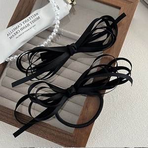Detail of elegant black multi-layer ribbon bow hair clips on a velvet jewelry display tray