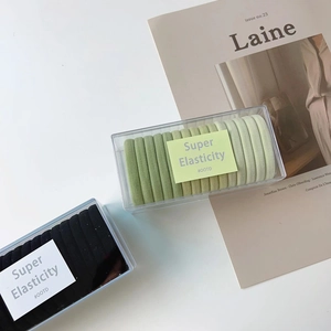 Detail view of high elasticity hair ties in black and green stored in a transparent box