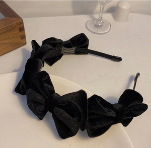 Detailaufnahme des schwarzen Samthaarbandes mit fünf Schleifen und Handmade-Etikett