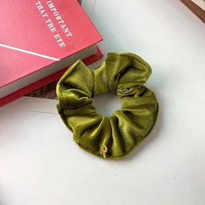 Chouchou en velours vert olive avec pendentif lettre R dorée sur table blanche
