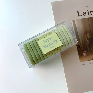 Green seamless elastic hair ties set neatly organized in a clear acrylic storage box