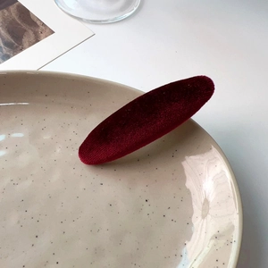 French vintage wine red velvet sponge hair clip on a minimalist ceramic plate