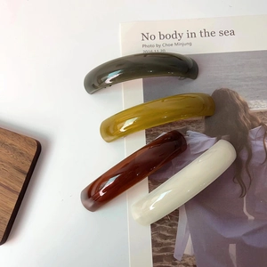 Detail showing acetate hair clips in dark green, yellow, amber brown, and ivory white colors