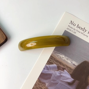 Detailed close-up of amber resin hair clip showing smooth curved marble texture on white background