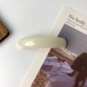 Macro detail of elegant cream white acetate hair clip with curved glossy finish