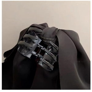 Détail du grand nœud noir en tissu et du mécanisme de la pince crabe au style élégant