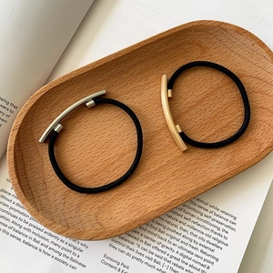 Minimalist elastic hair ties with gold and silver metal tubes on a decorative tray