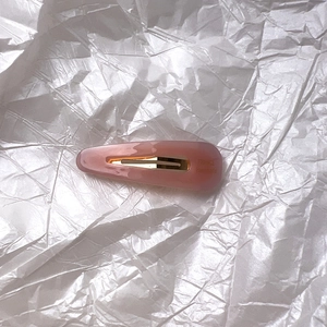 Barrette à cheveux minimaliste en acétate rose pêche avec ressort doré sur papier argent