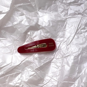 Détail macro d'une pince à cheveux en acétate rouge avec lettrage doré fait main