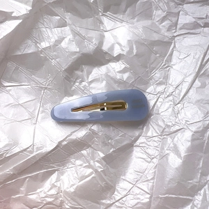 Détail d'une pince à cheveux en acétate bleu clair avec fermeture en métal doré
