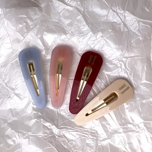 Détail de quatre barrettes en acétate faites à la main en bleu, rose, rouge et beige
