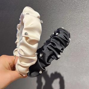 Close-up of pleated satin headbands in black and cream with sparkling rhinestones