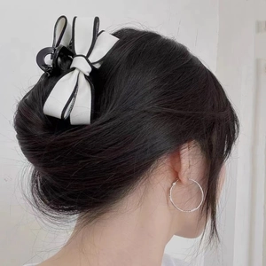 Elegant large black and white bow hair claw clip and silver hoop earrings on a model