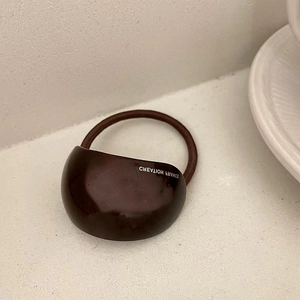 Detail of dark brown resin accessory with Creation France text and elastic hair band