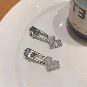 Vintage silver hair clips set with pearls and rhinestones on a ceramic dish