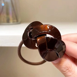 Close-up of coffee brown resin knot hair tie with France Creation engraving detail