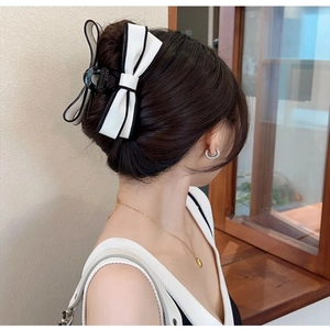 Detail view of a large white ribbon hair claw clip with black piping on a model hairstyle