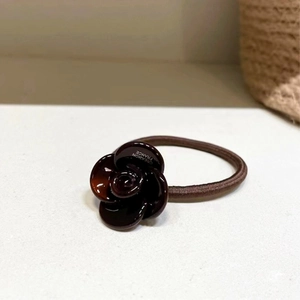 Detail view of a vintage dark brown resin rose hair tie with Creation France engraving