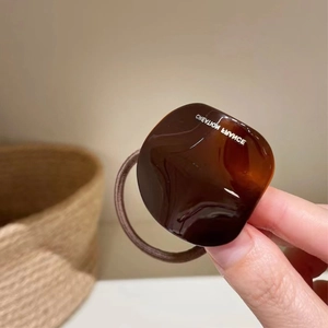 Detail of tortoiseshell resin charm with Creation France text on brown hair tie