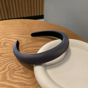 Serre-tête en cuir gris foncé rembourré effet satiné sur une table en bois