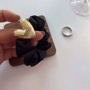 Elegant black satin hair scrunchie with a gold heart-shaped metal charm and engraving