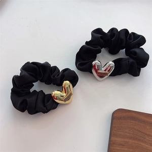 Detail of black silk scrunchies featuring heart metal charms with Lovedays engraving