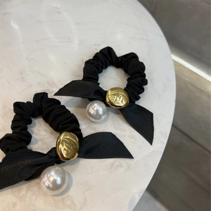 Gros plan de chouchous noirs avec nœuds en satin, boutons dorés et perles élégantes