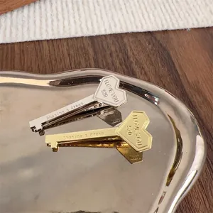 Unique key-shaped heart hair clips in polished gold and silver metal finishes