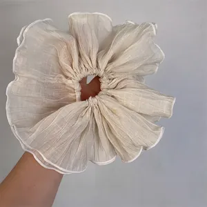 Oversized beige pleated hair scrunchie with white piped edges and elegant texture