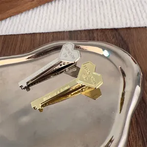 Close-up of gold and silver heart-shaped key hair clips with engraved romantic text