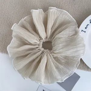 Close-up of beige chiffon scrunchie showing pleated fabric texture and elastic band detail