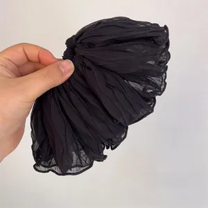 Detailed view of black pleated chiffon scrunchie with fine vertical textured fabric