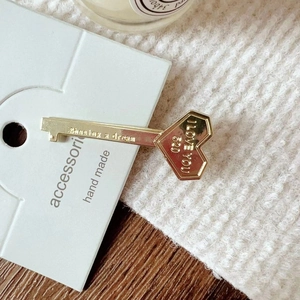 Close-up of golden heart key hair clip with I LOVE YOU engraving on a display card