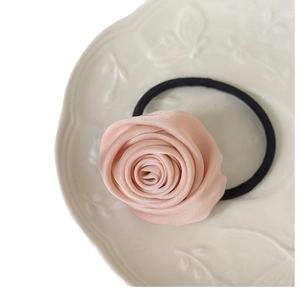 Elegant pink satin rose flower hair scrunchie on a white decorative ceramic plate