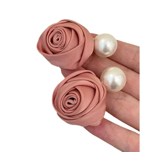 Pince à cheveux fleur rose poudré avec perle élégante tenue dans la main